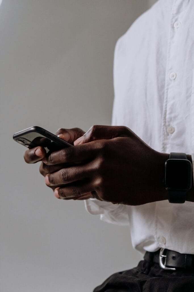 a man wearing white shirt is using iPhone for messaging