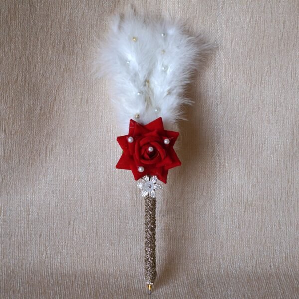 DSC07673 “Close-up of a decorative Nikah signing pen featuring a glittery lace-wrapped barrel, a red artificial rose with pearl-studded floral accents, and white feather plumes.”